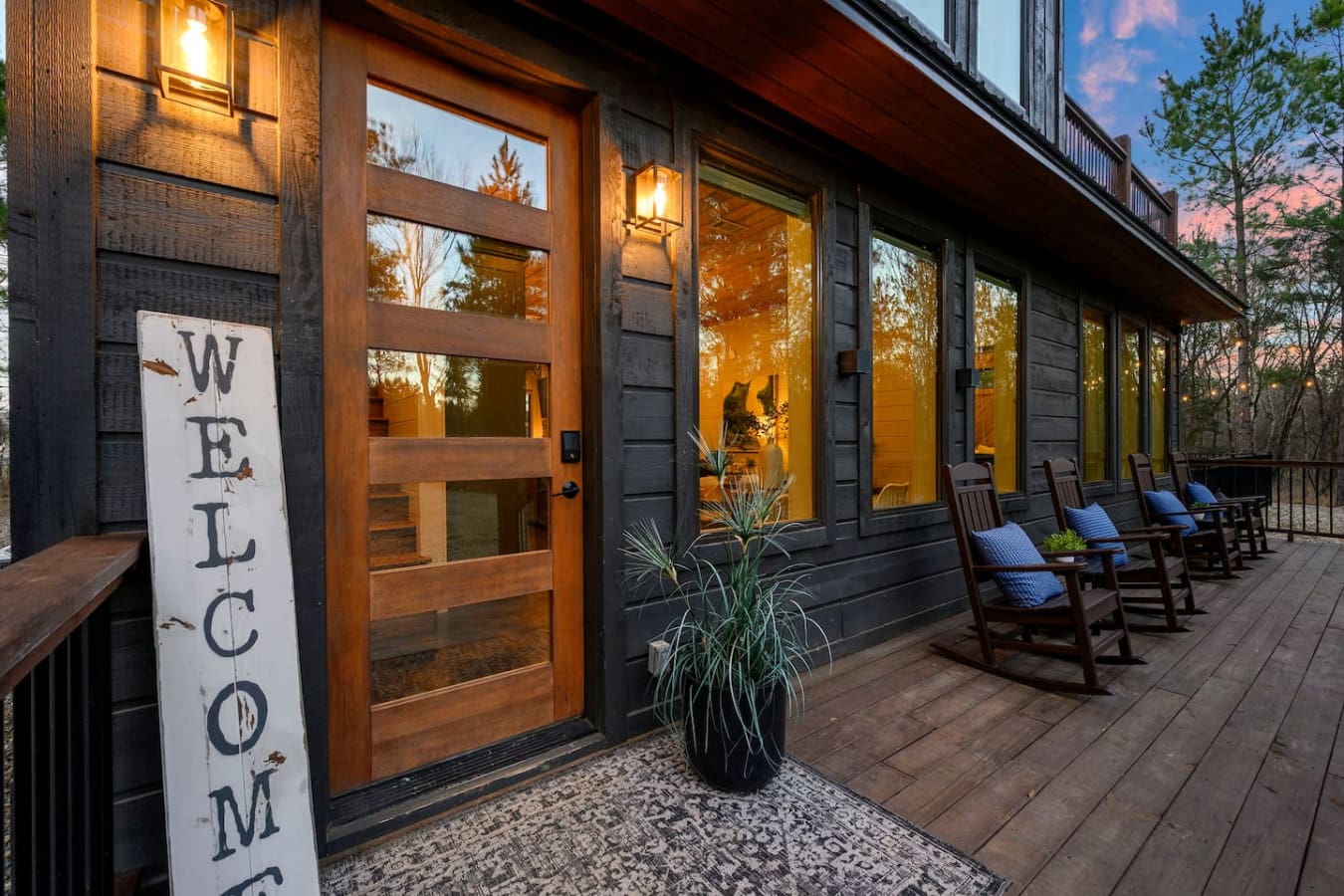 This stunning modern retreat features a spacious covered porch with comfortable seating and floor-to-ceiling windows overlooking the mountains.