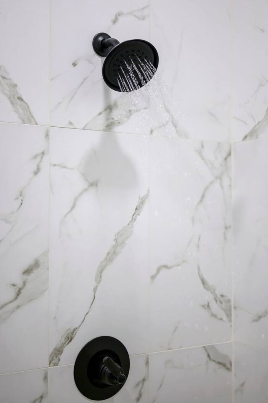This sleek marble shower setup with rainfall and body jets is basically a spa day every time you step in.