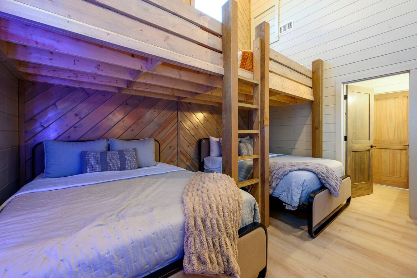 This cozy loft bedroom features two queen beds with rustic wood beams and ambient lighting perfect for a relaxing getaway.