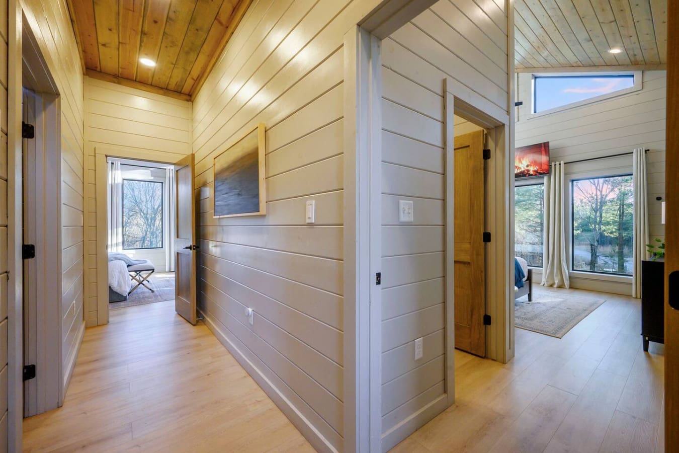 This bright hallway connects multiple bedrooms with beautiful natural light and hardwood floors throughout.