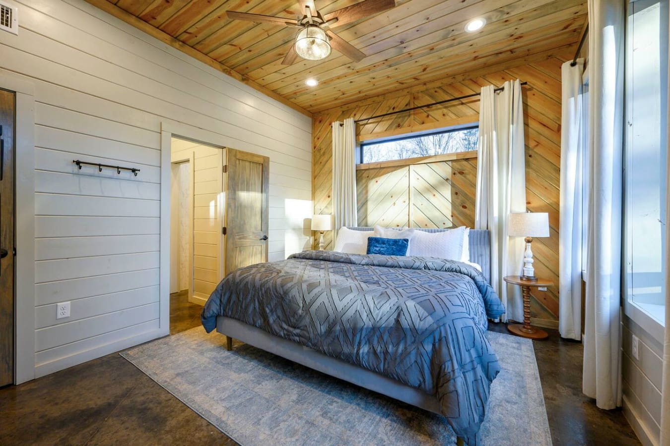 This stunning master bedroom features soaring wood ceilings, a four-poster bed, and gorgeous water views.
