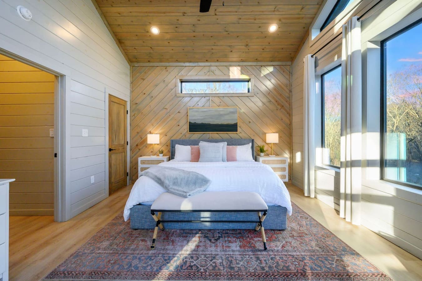 This modern cabin bedroom has soaring wood ceilings, floor-to-ceiling windows, and those stunning mountain views.