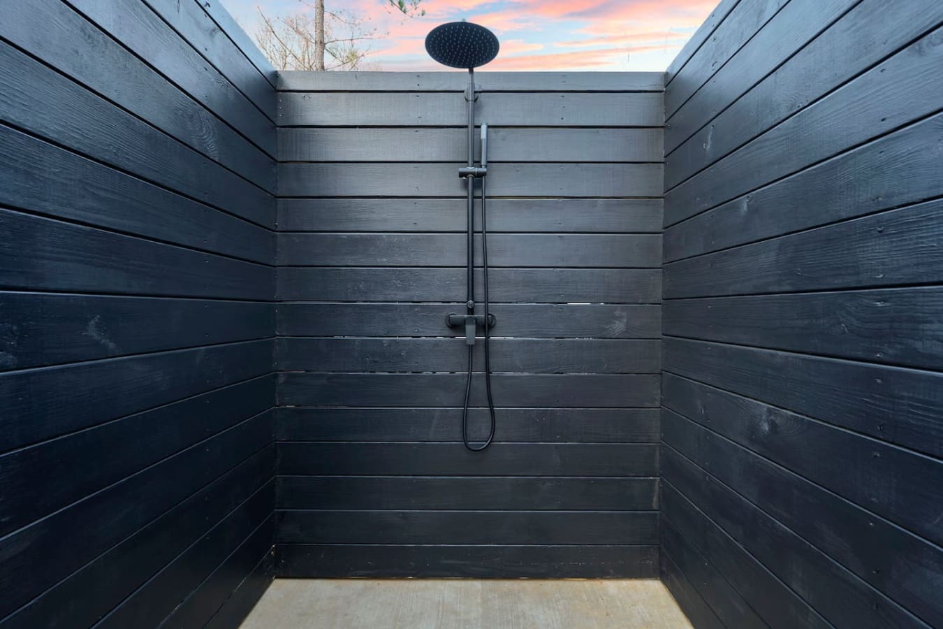 This outdoor shower offers a luxurious open-air experience with stunning sky views and sleek black wood finishes.