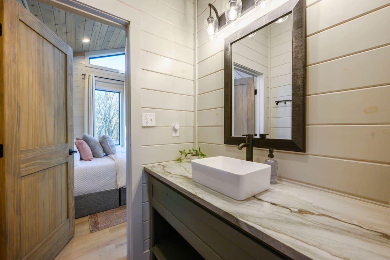 This pristine bathroom features a sleek vessel sink, marble countertop, and direct access to the cozy bedroom beyond.