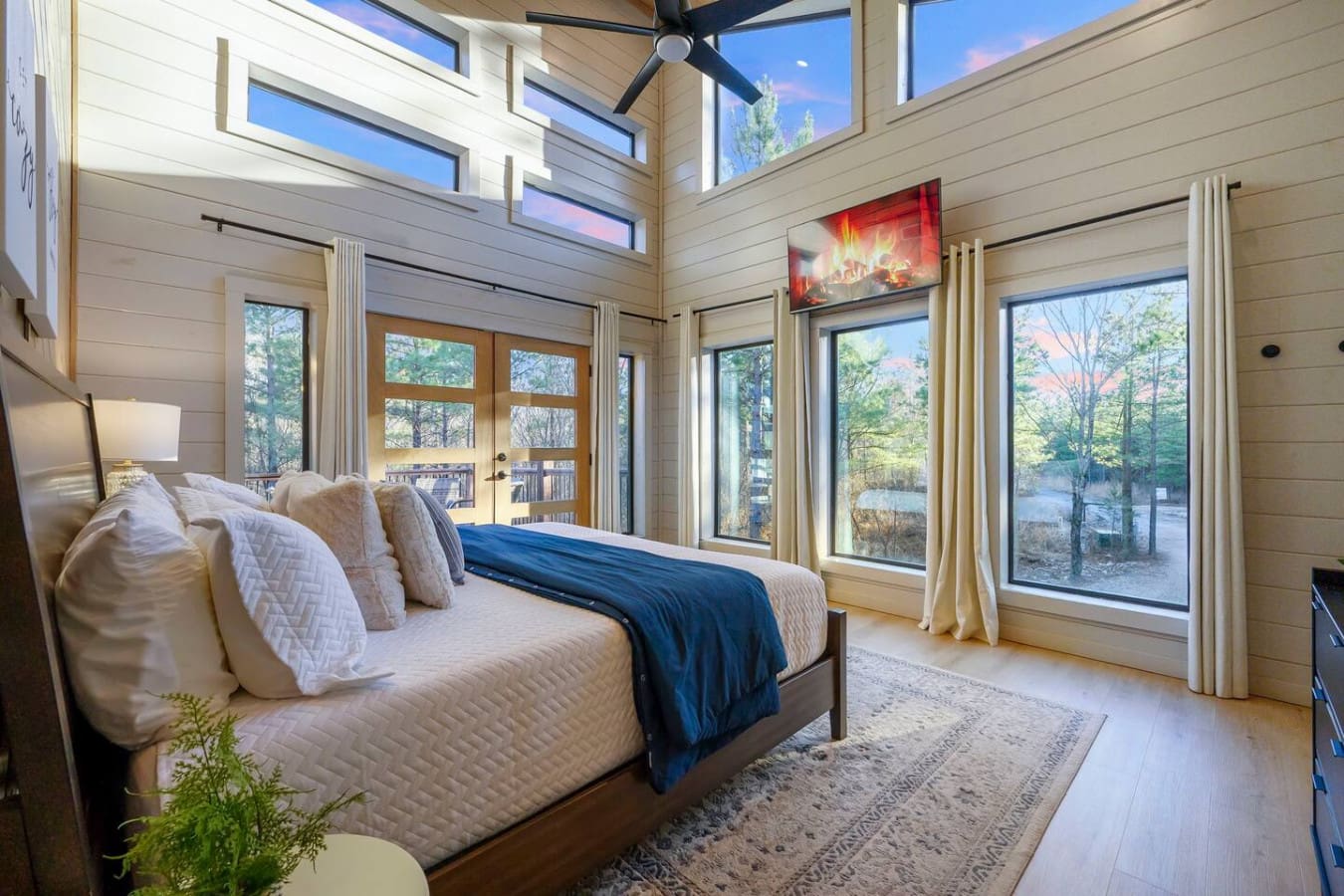 Wake up to stunning lake views from this luxe bedroom with soaring ceilings and walls of windows.