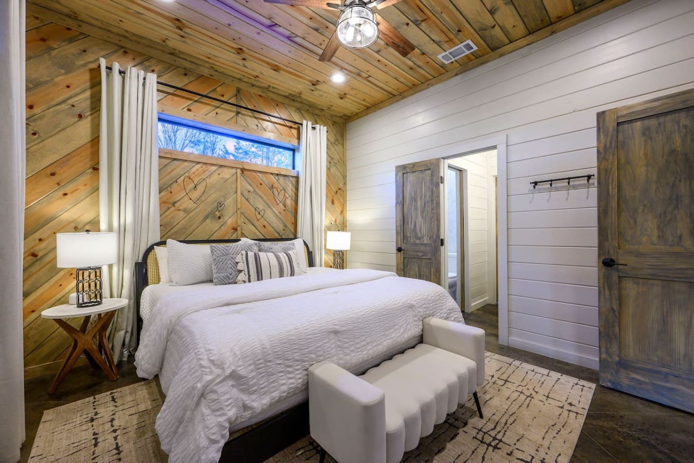 This master bedroom has everything—a dreamy canopy bed, soaring wood ceilings, and those barn doors are *chef's kiss*.