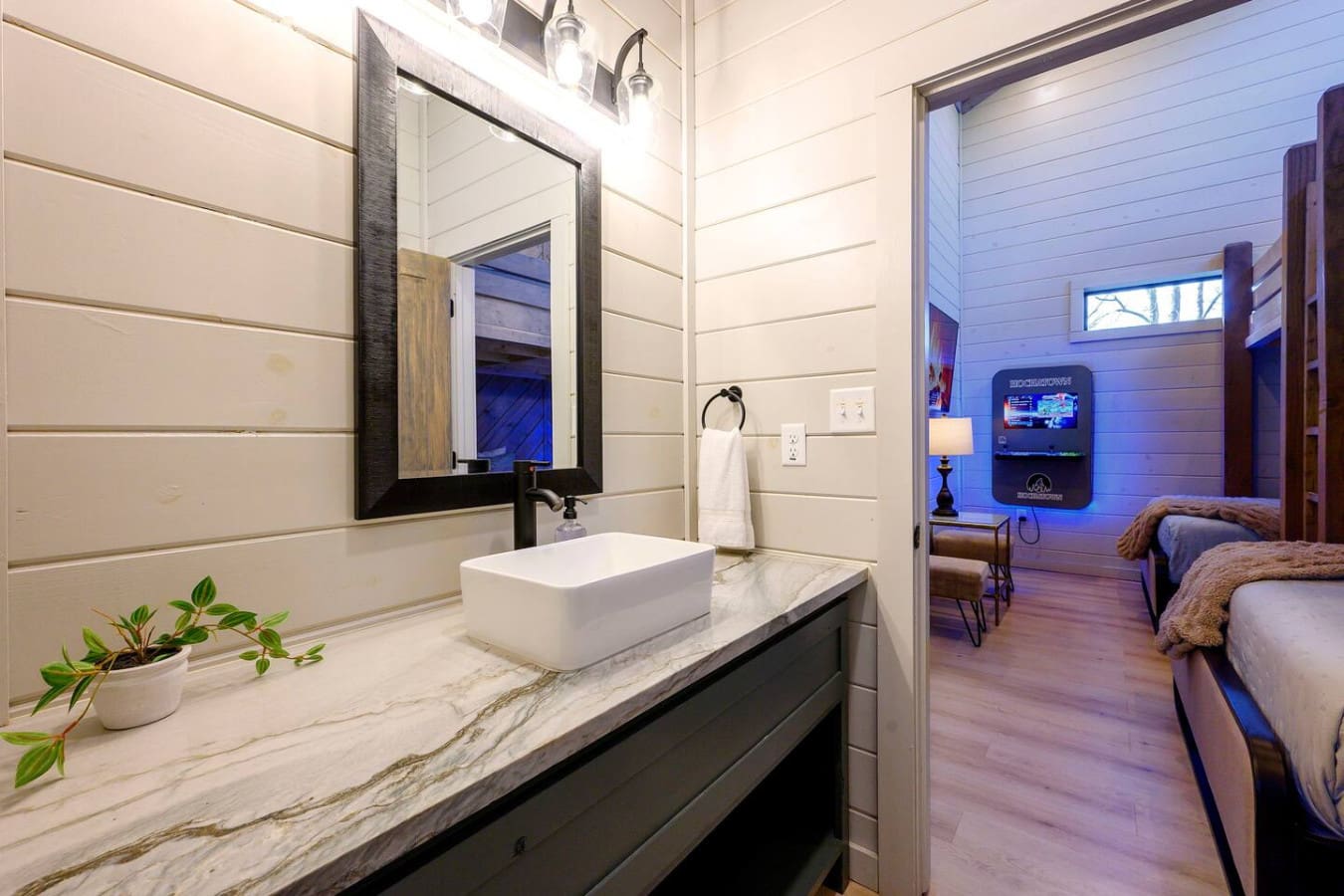 This modern ensuite bathroom features a sleek marble vanity, vessel sink, and direct access to the bedroom with ambient lighting.