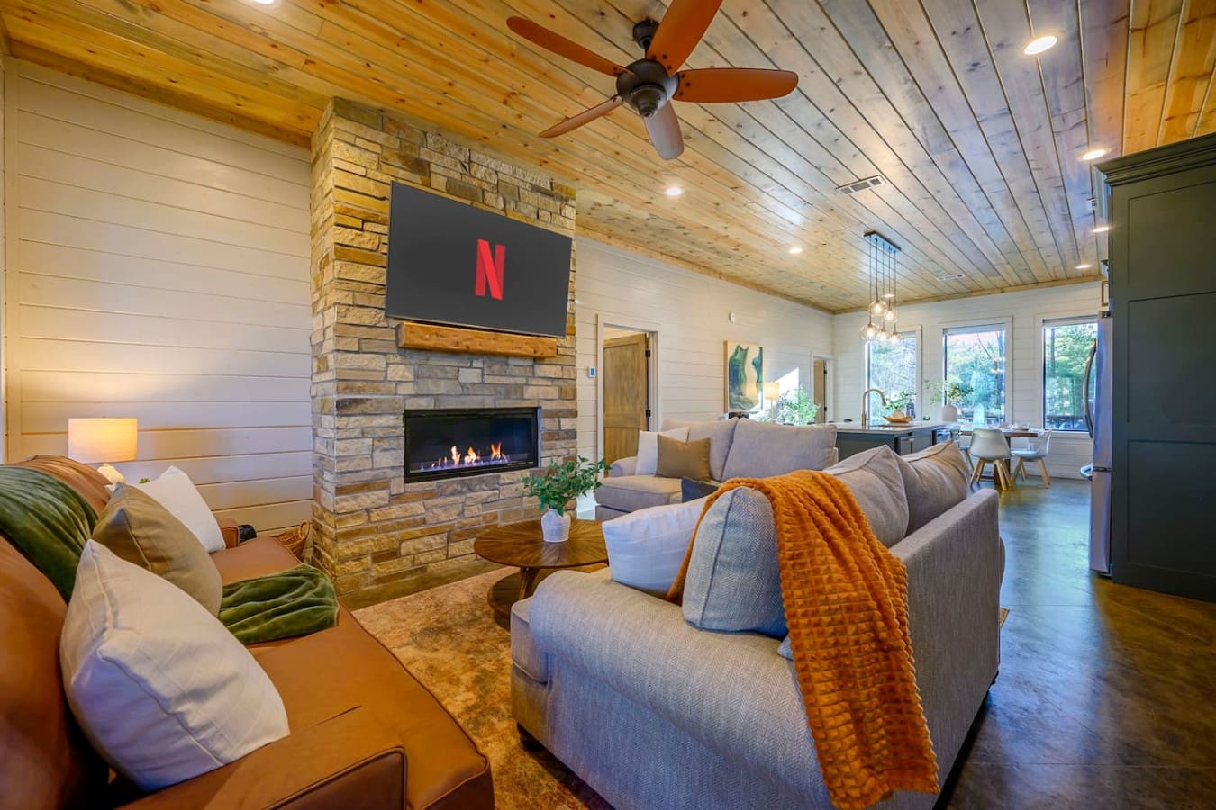 This open-concept living room is basically built for binge-watching with that stone fireplace, smart TV, and super comfy seating.
