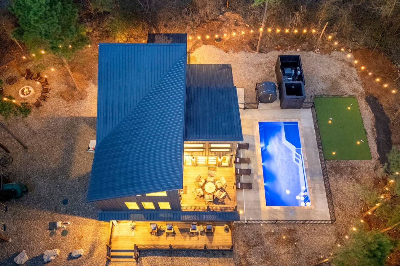 This stunning modern property features a resort-style heated pool, spacious deck, and beautifully landscaped grounds lit for evening ambiance.