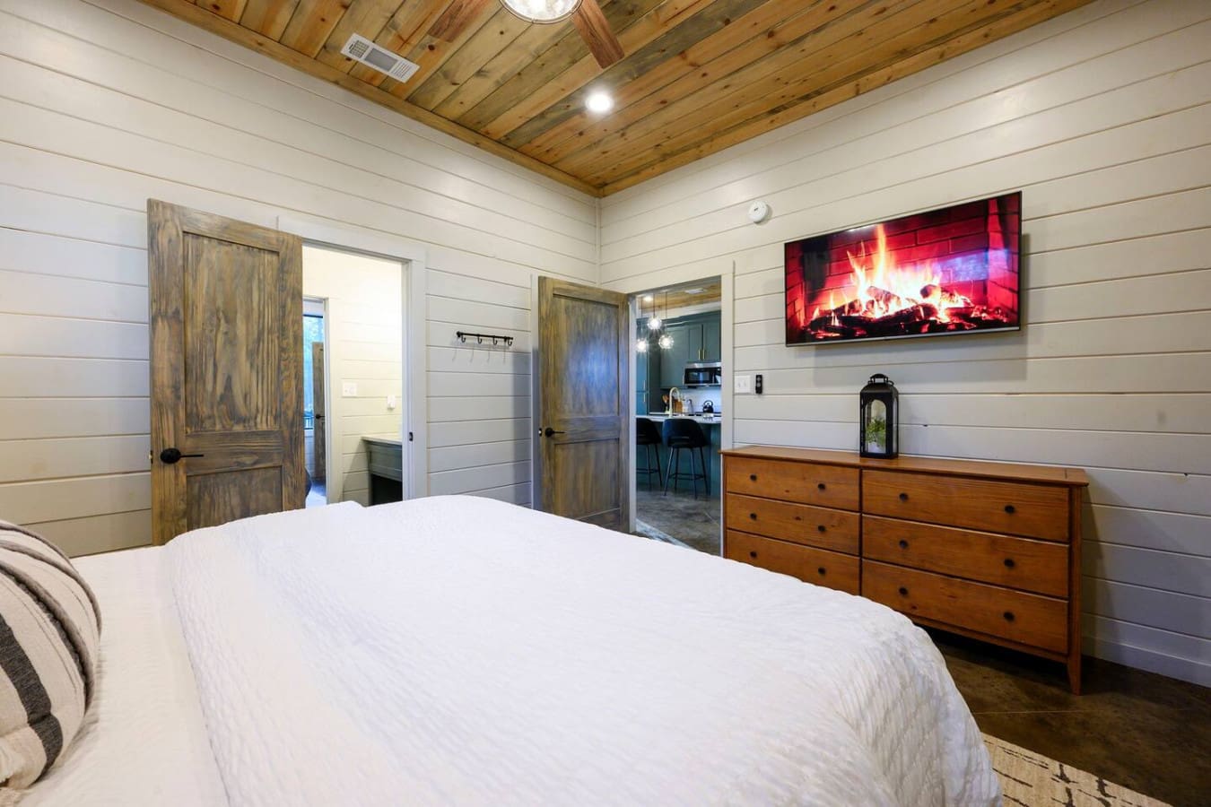 This primary bedroom suite features a cozy fireplace view, rustic wood doors, and direct access to the kitchenette.
