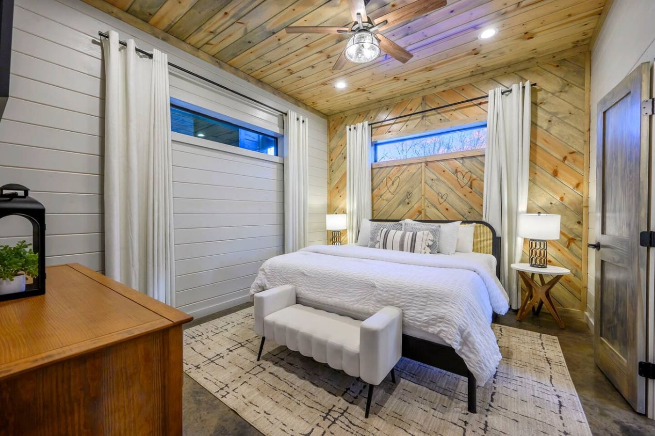 This modern cabin bedroom features soaring wood ceilings, a canopy bed, and walls of windows with mountain views.