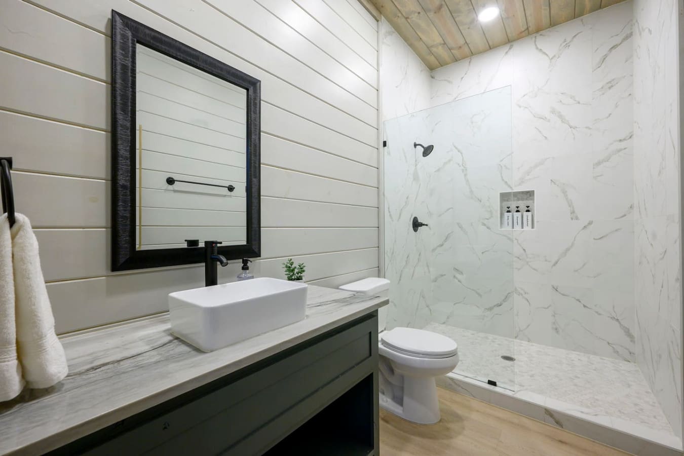 This spa-like bathroom features marble finishes, a vessel sink, and a spacious walk-in shower.