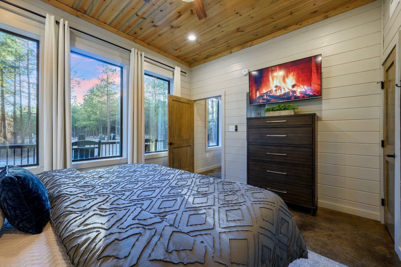 Wake up to forest views and modern comforts in this spacious bedroom with a fireplace and private deck.