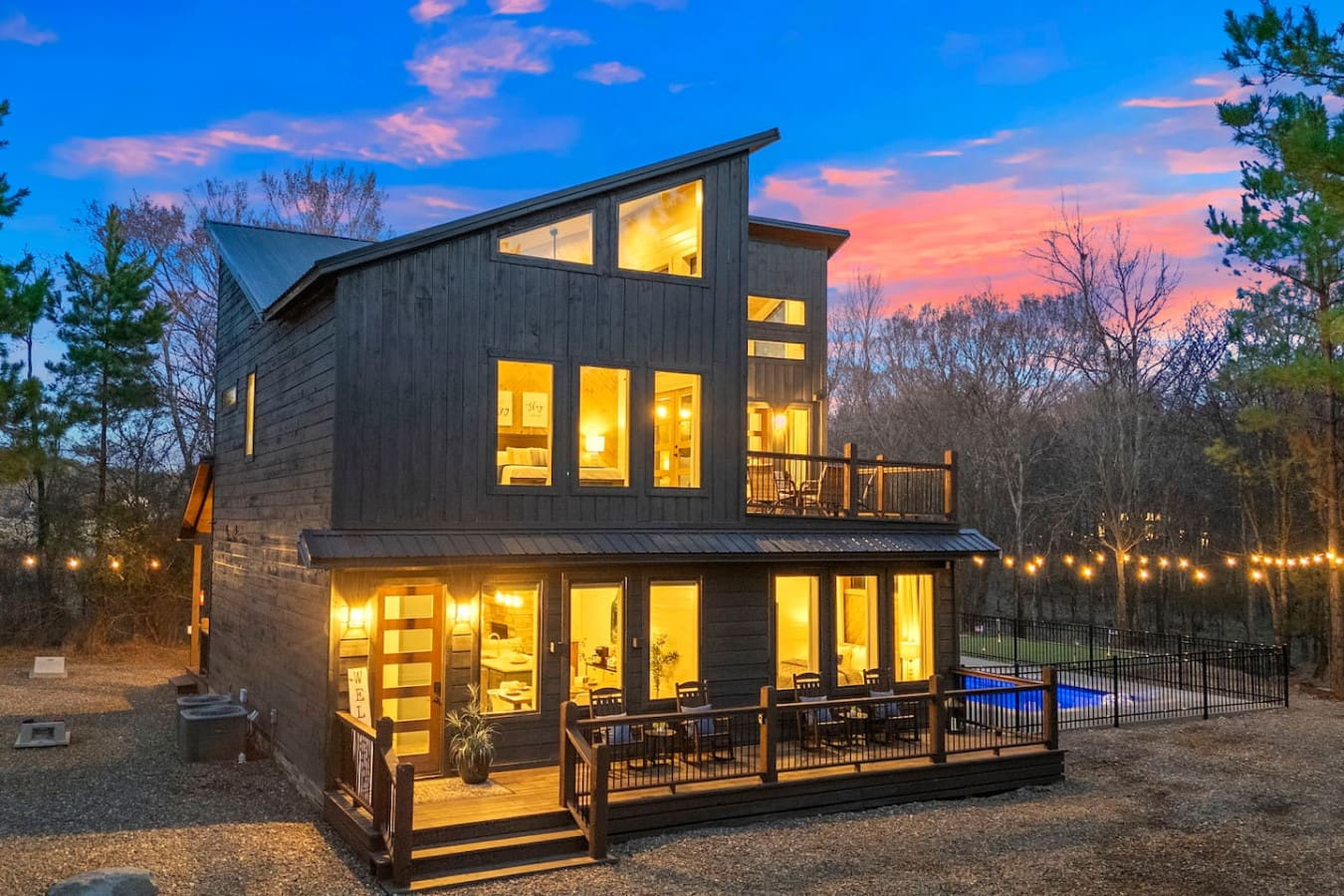 This stunning modern home glows against a dramatic sunset with a resort-style pool and wrapped deck perfect for entertaining.
