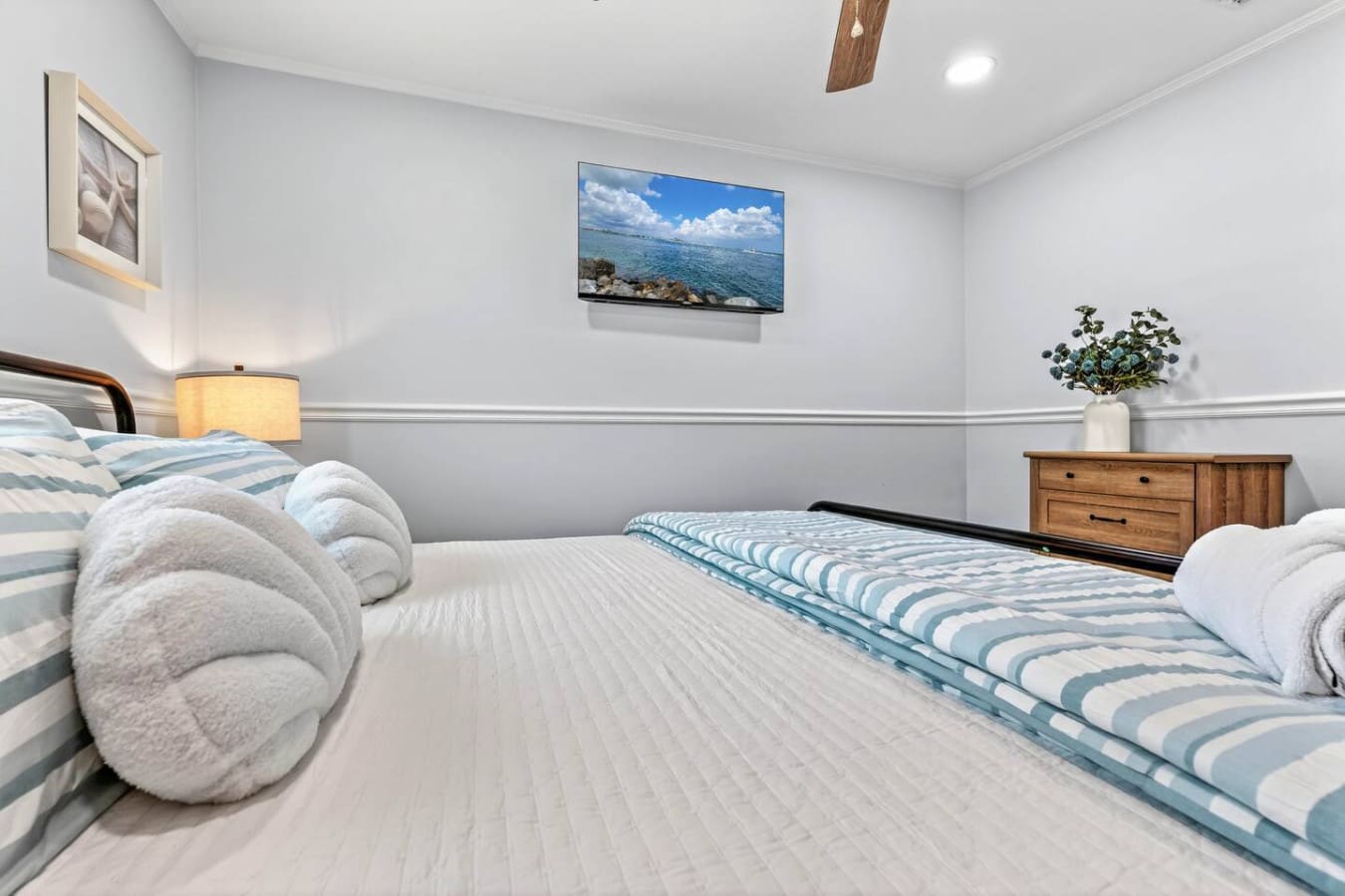 Spacious guest bedroom with two comfy beds, ocean views on the TV, and plenty of natural light.