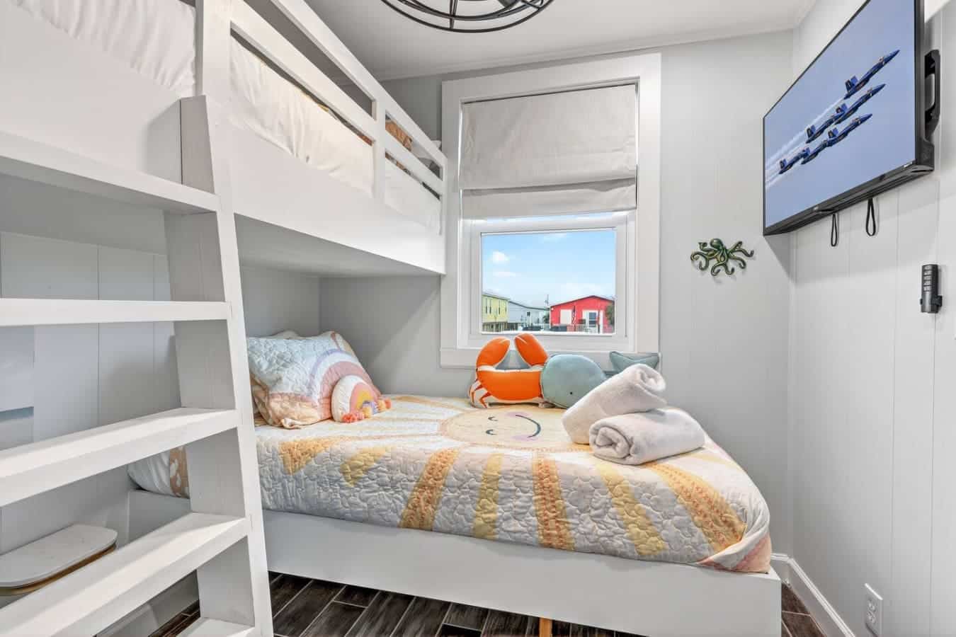 Cozy bunk room with a view of colorful beachfront buildings and all the storage you need.