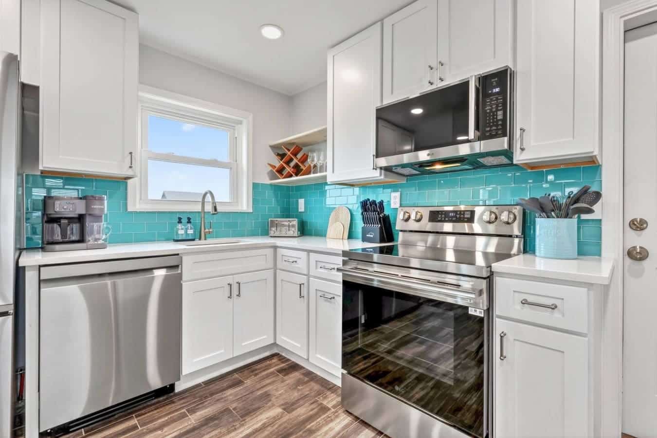 This bright, modern kitchen features crisp white cabinetry, stainless steel appliances, and a gorgeous turquoise tile backsplash.