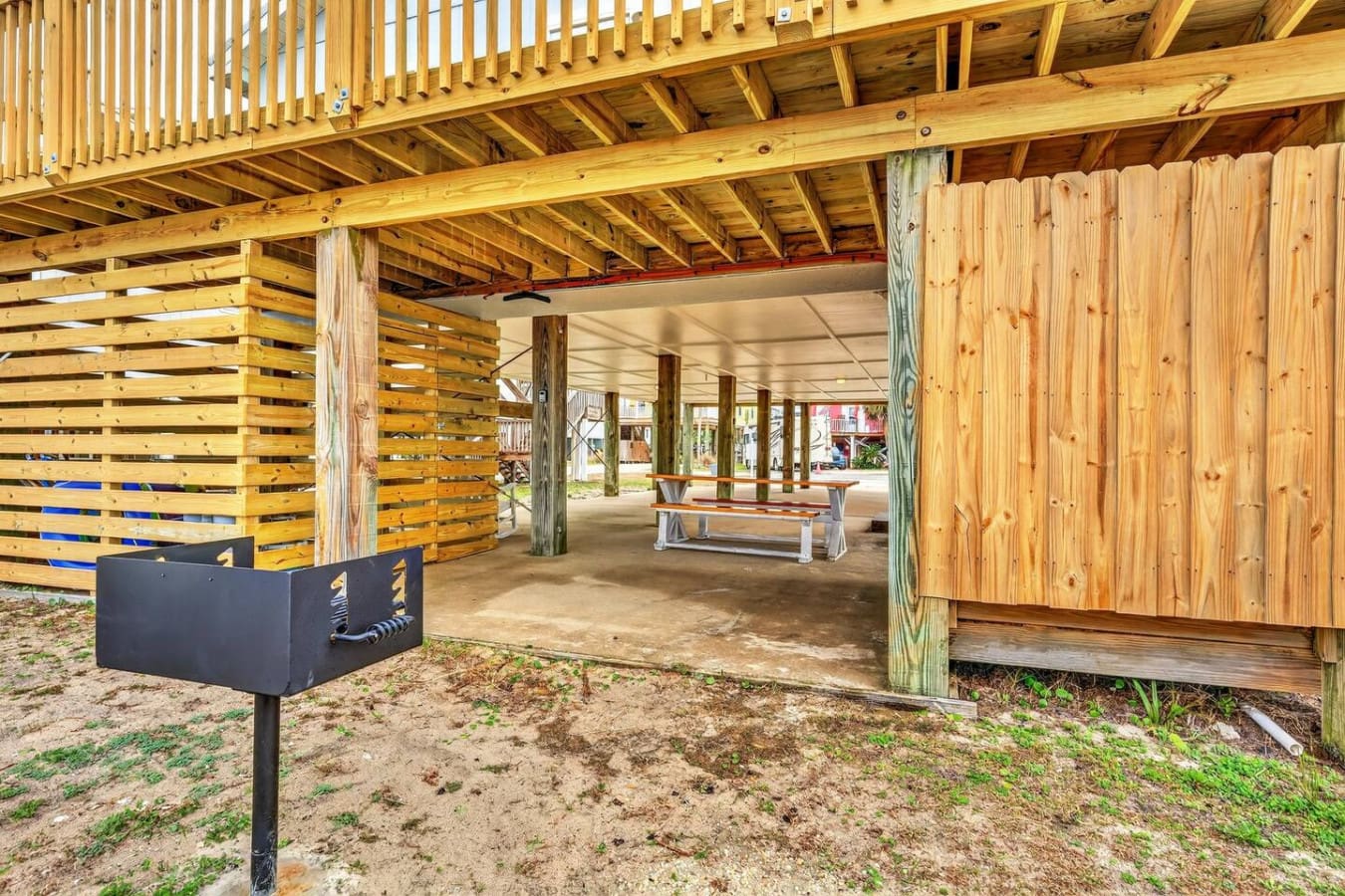 Spacious covered pavilion with picnic tables and rustic wood beams, perfect for outdoor gatherings.