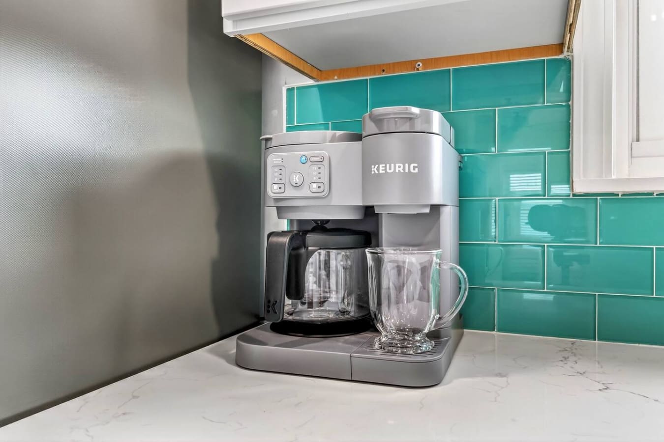 Modern kitchen features sleek stainless steel appliances and vibrant turquoise subway tile backsplash.
