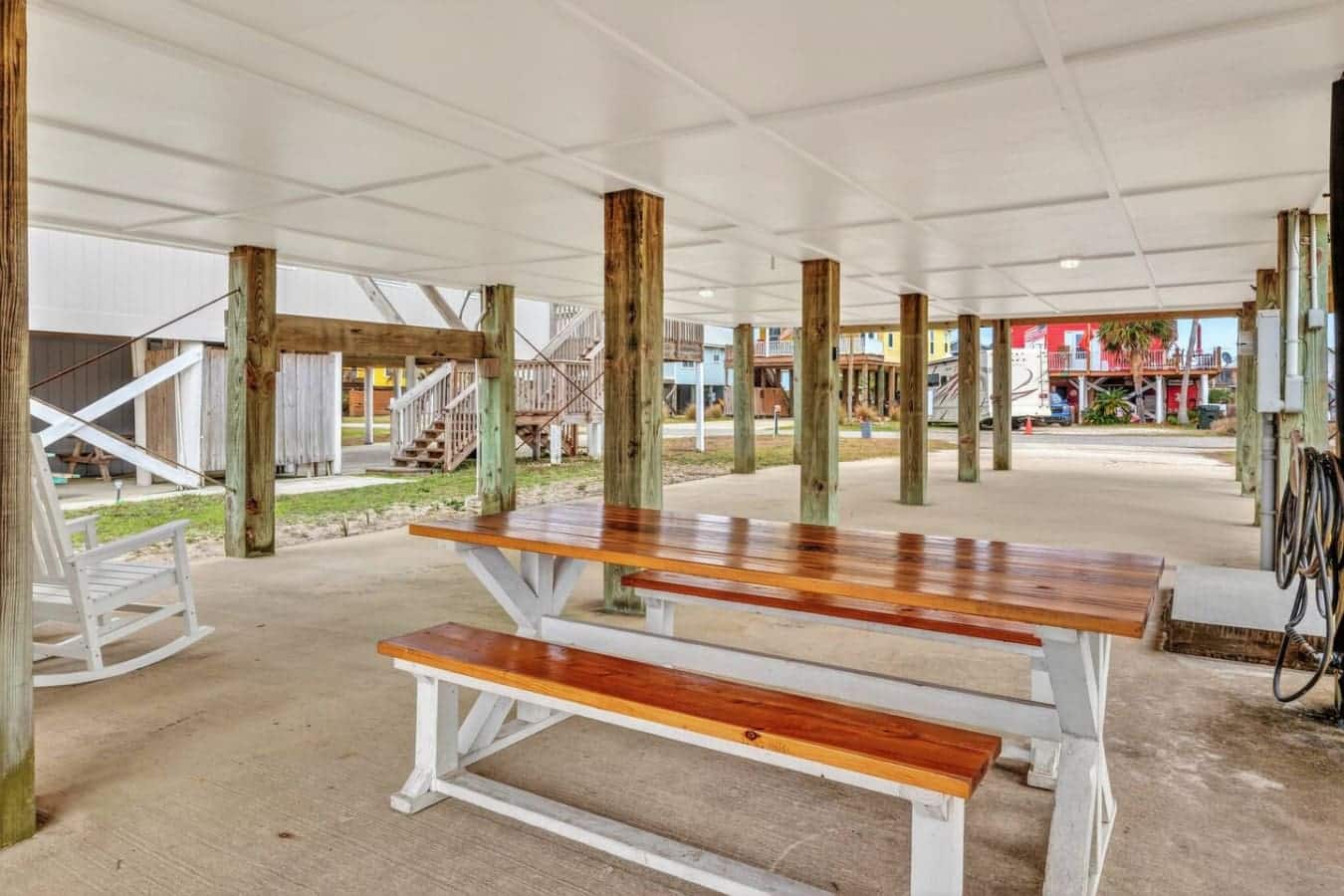 Covered gathering space with picnic tables and weathered wood posts, perfect for hanging out with the beach community.