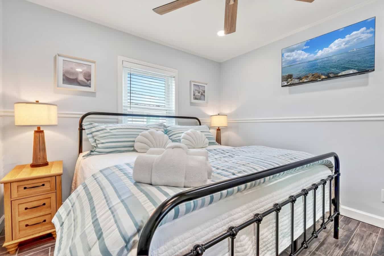 This bright, airy guest bedroom features a cozy metal bed with crisp coastal bedding and ocean-view artwork throughout.
