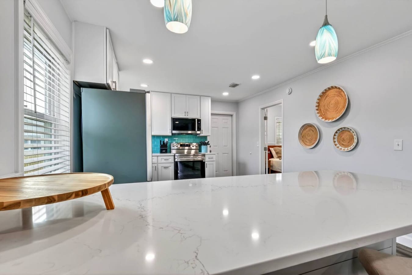 Modern chef's kitchen with sleek white cabinetry, turquoise accents, and a sprawling marble island perfect for entertaining.