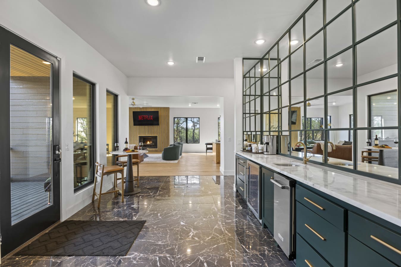 The wet bar and mirrored backsplash greet you at the entry, with the living room fireplace glowing just beyond.