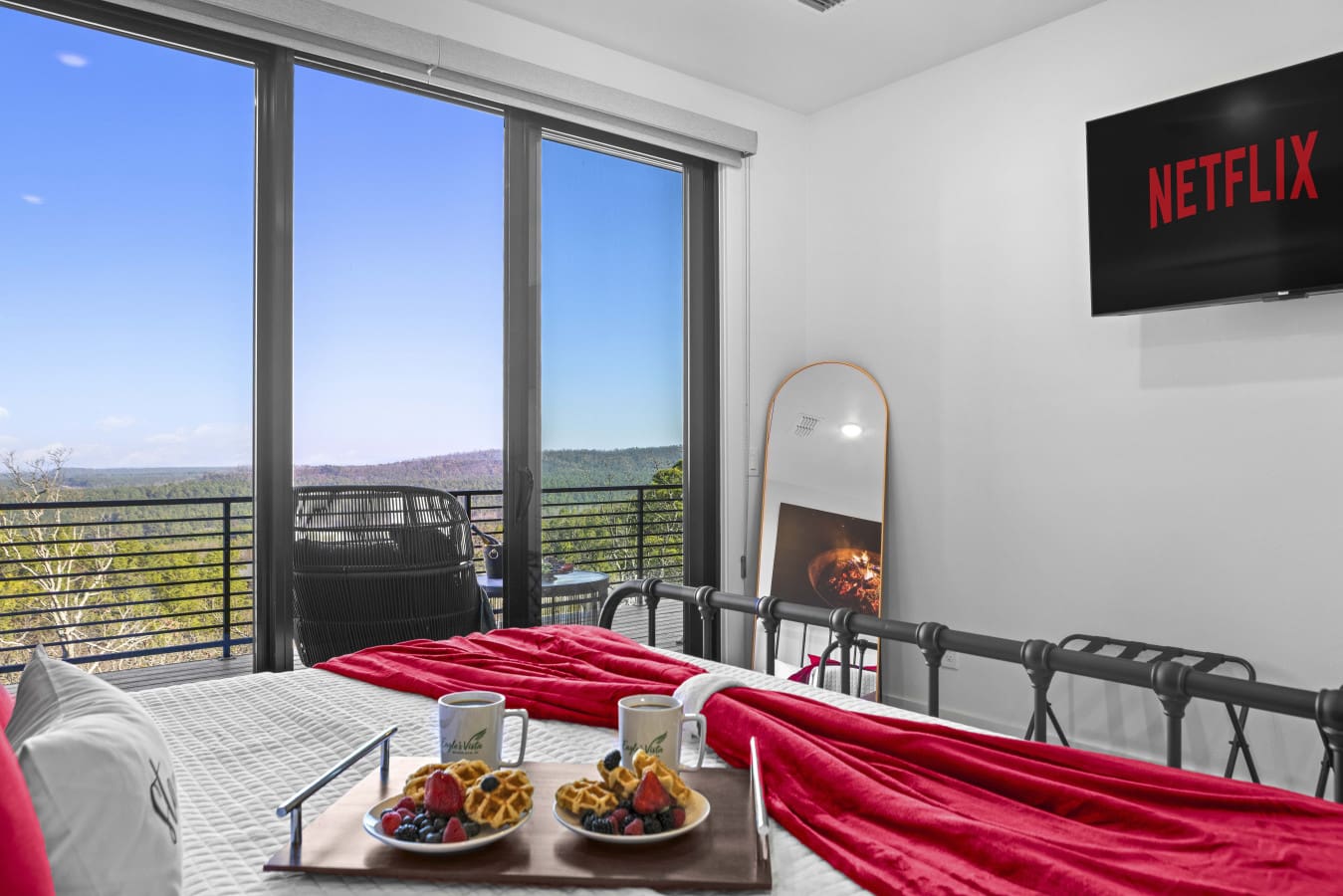 Waffles and berries in bed, Netflix queued up, and a fireplace glowing while the forest stretches out beyond the balcony.