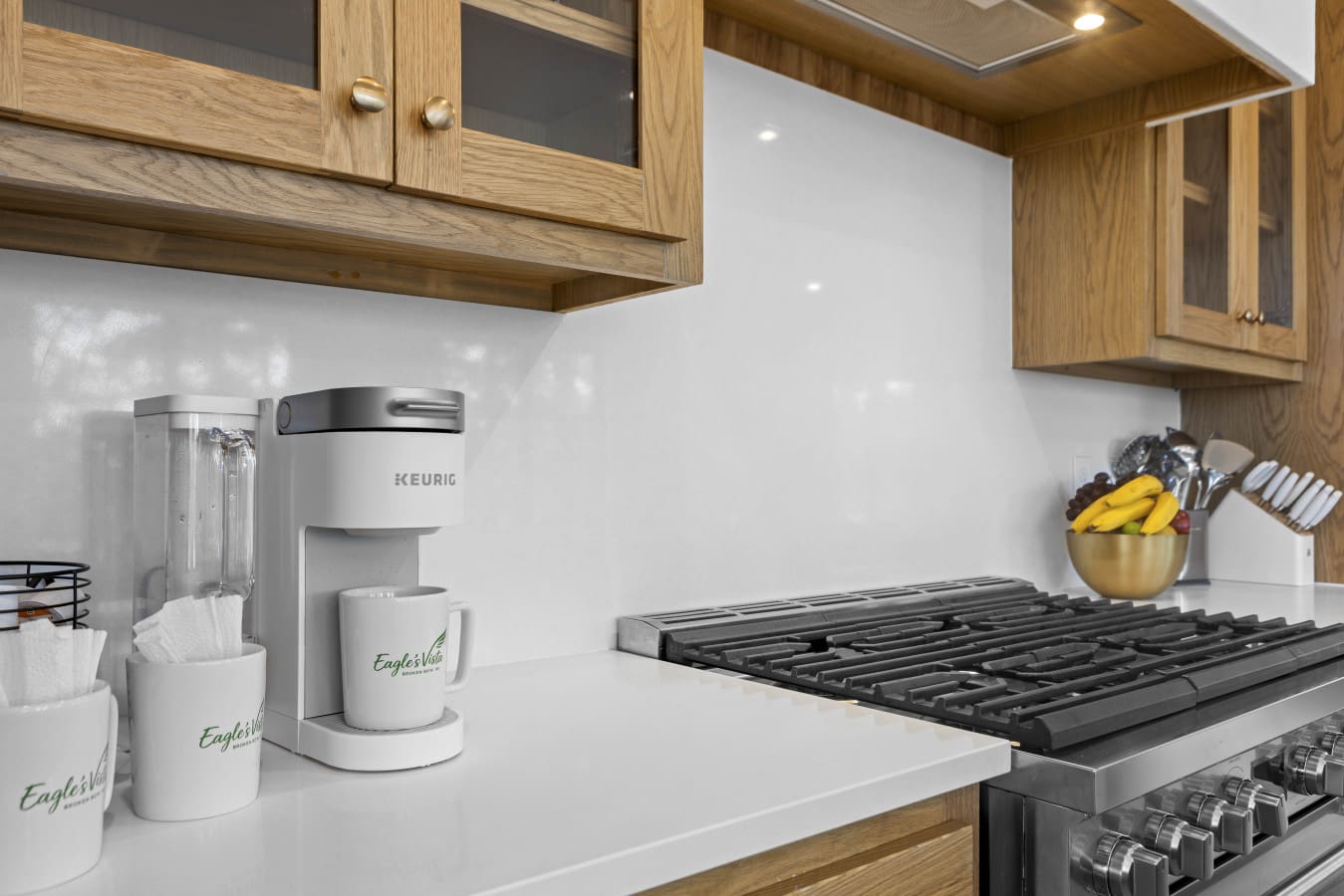 Morning coffee setup is ready to go with a Keurig and branded mugs right next to the gas range.