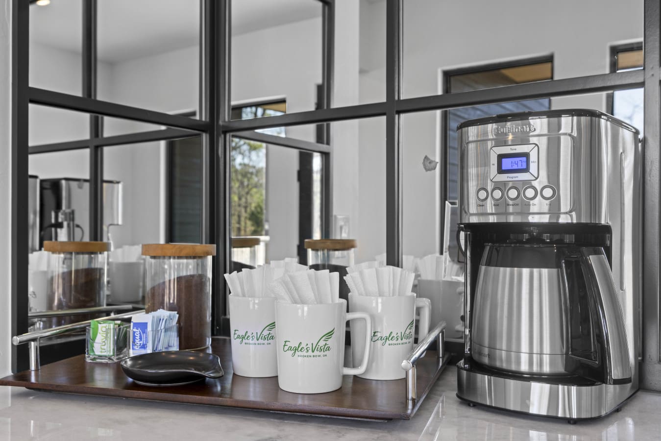 The coffee station's got branded mugs, fresh filters, and what looks like two kinds of ground coffee ready to go.