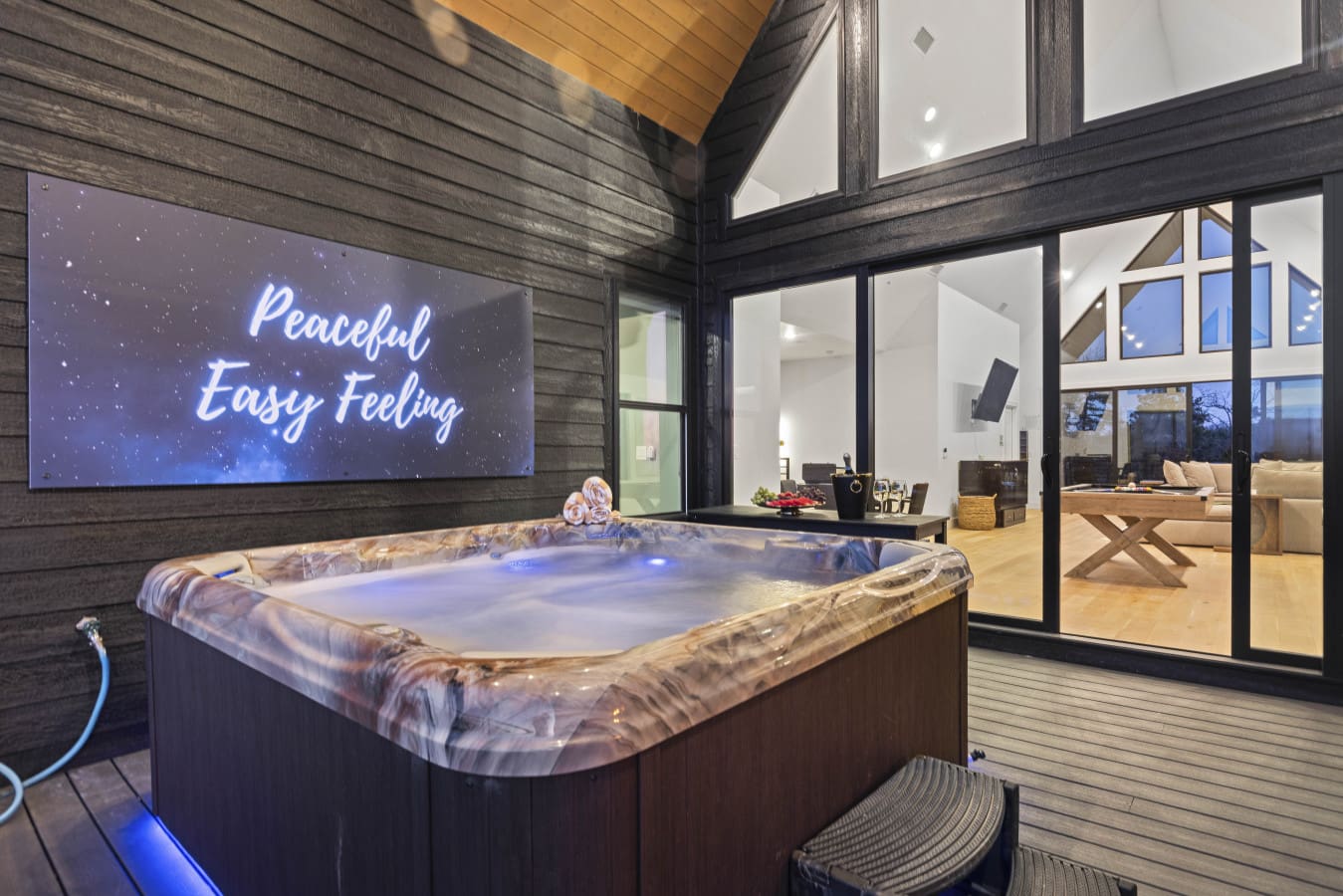The hot tub's ready and glowing blue under that "Peaceful Easy Feeling" sign — pretty on-brand for a Broken Bow evening.