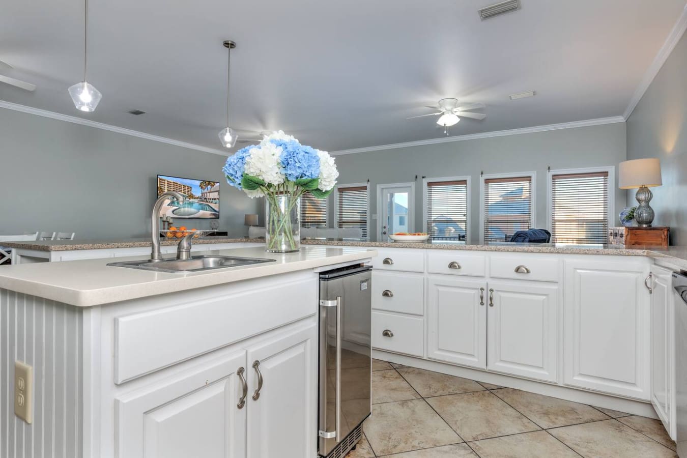 This bright, airy kitchen with its crisp white cabinetry, sparkling granite counters, and those gorgeous blue hydrangeas in the center is basically screaming "gather everyone around and let's cook something amazing together."