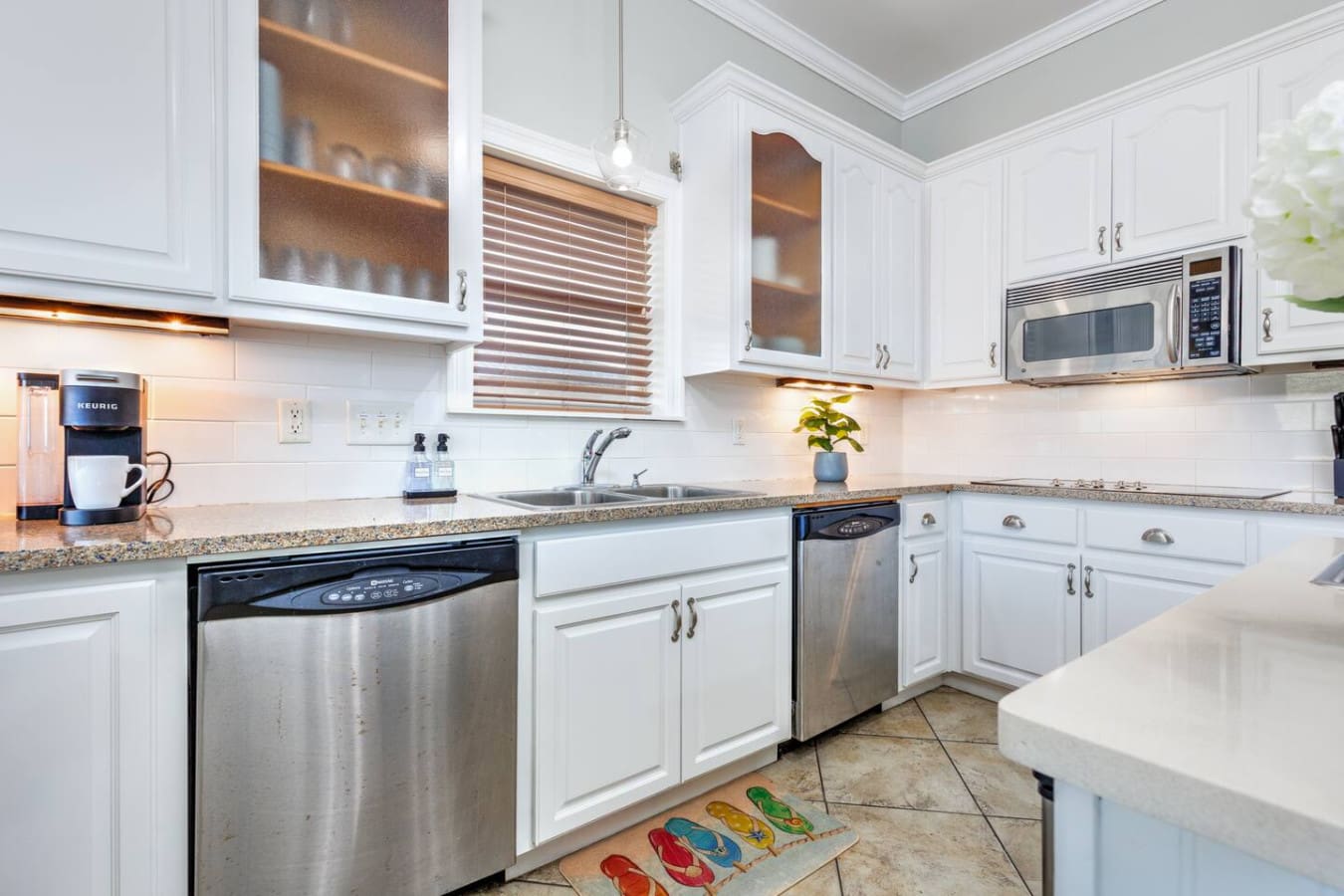 This pristine white kitchen with its granite countertops, stainless steel appliances, and warm under-cabinet lighting is basically the heart of this place where you can whip up anything from quick snacks to full family dinners.