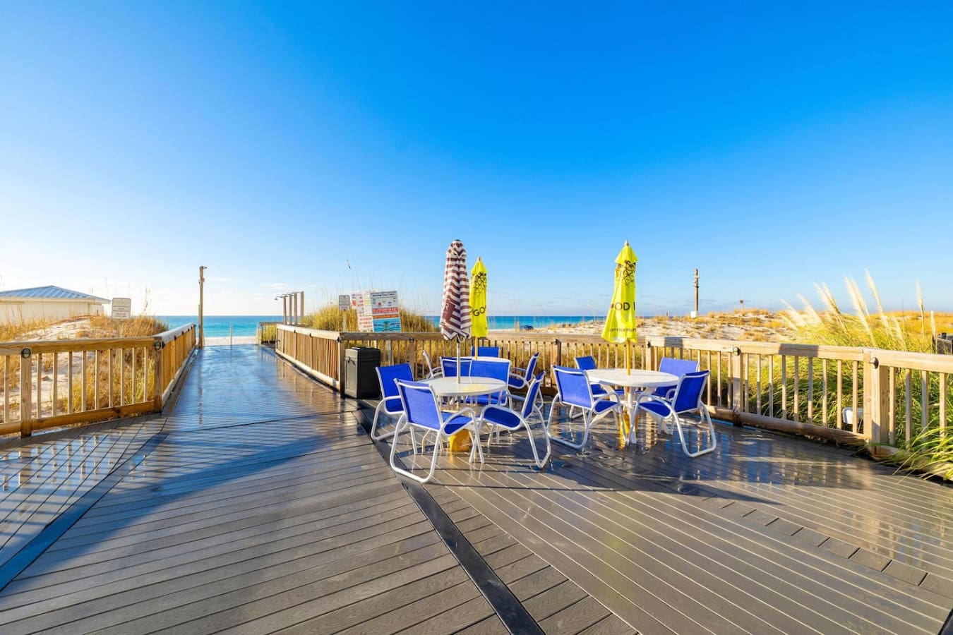 Step out onto this beachfront boardwalk and you'll understand why people camp out in those blue loungers all day—it's basically your front-row seat to uninterrupted ocean views, wide-open sky, and that perfect stretch of sand where time just stops.