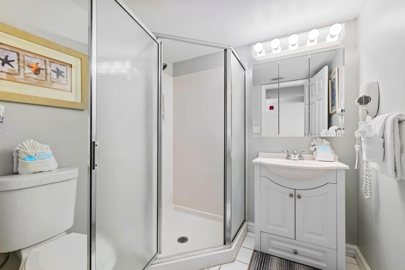 This bright, efficient bathroom has everything you need to rinse the salt and sand away—crisp white cabinetry, plenty of counter space, and that shower stall that's basically your reset button between beach adventures.