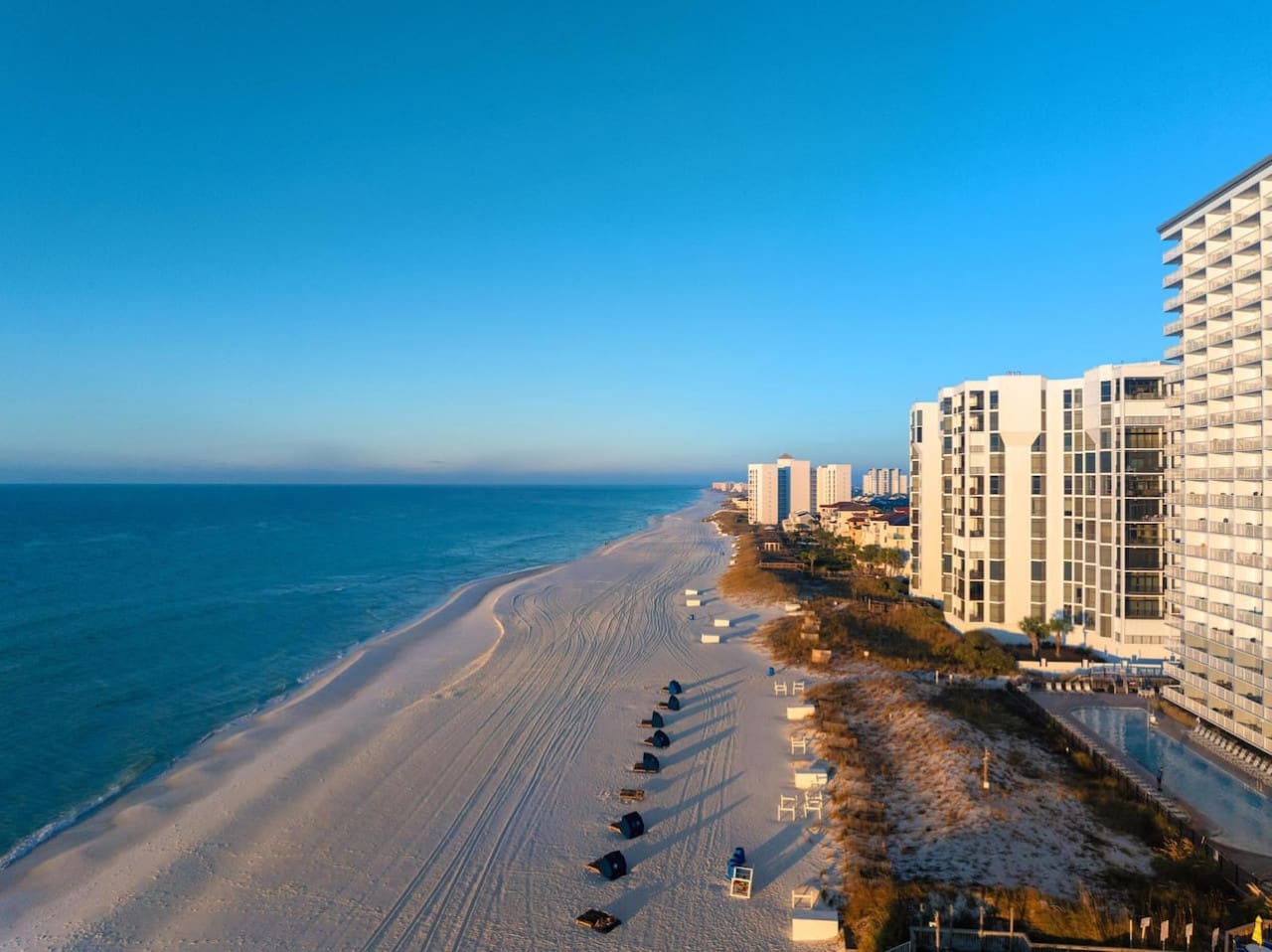 Wake up to this view and you'll understand why people come back to Pelican Beach Resort year after year—miles of pristine sand, that impossibly blue water, and high-rises that catch the golden light just right.