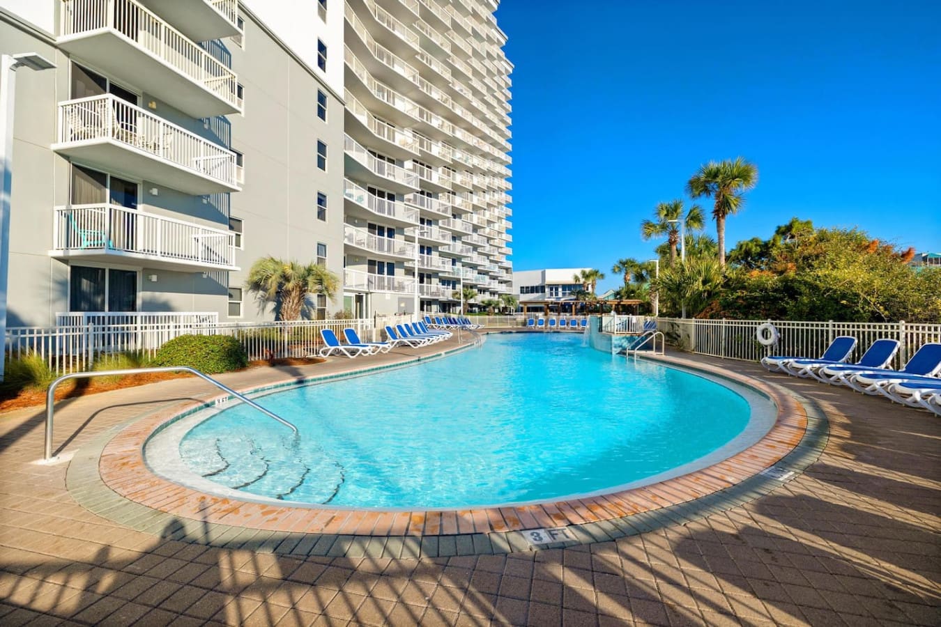 The resort pool curves out before you like it was designed just for this moment—crystal-clear water, palm trees swaying overhead, and that perfect stretch of lounge chairs waiting for you to claim your spot and disappear into the day.