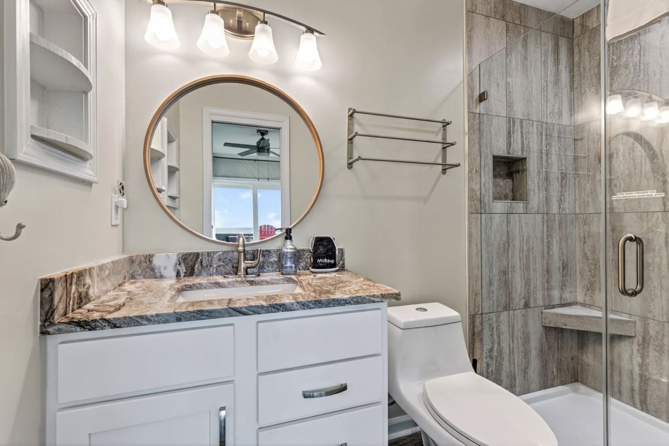 This spa-like master bath features a spa shower, marble countertops, and stunning ocean views through that gorgeous round mirror.