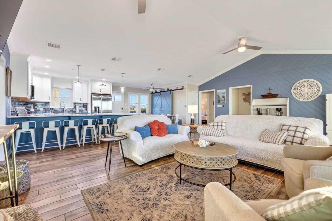 Open-concept living with gorgeous blue accent wall, white furnishings, and ocean views throughout this stunning coastal home.