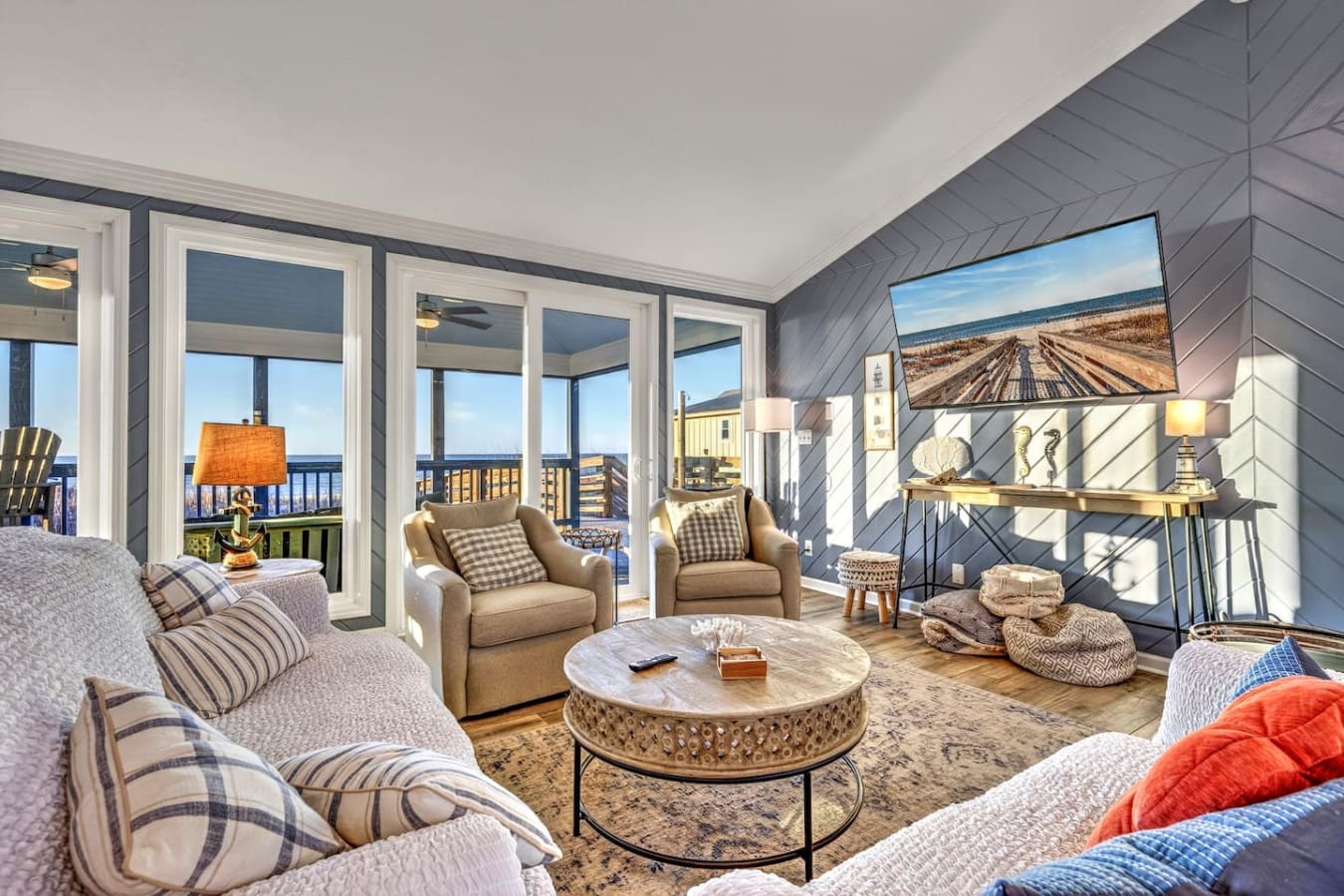 This stunning waterfront master suite features floor-to-ceiling windows, a marble coffee table, and panoramic ocean views from your private balcony.