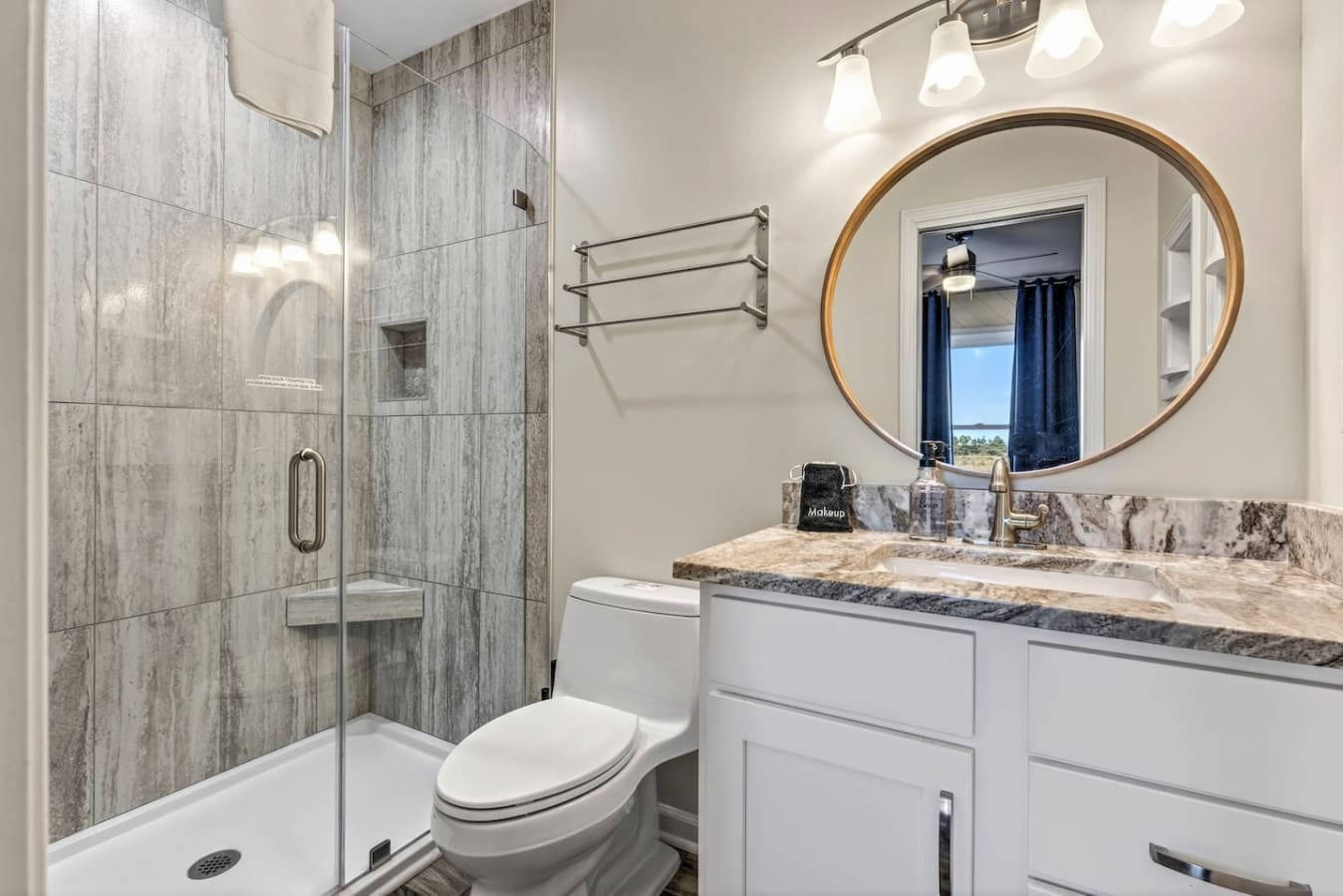 This spa-like master bath features marble finishes, a walk-in shower, and a stunning view through those blue curtains.