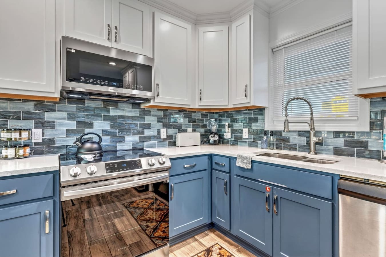 This stunning kitchen features blue cabinetry, a blue-green tile backsplash, and stainless steel appliances perfect for any home chef.