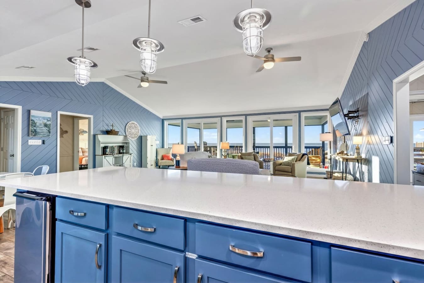 This open-concept beach house features stunning ocean views, soaring ceilings, and a massive blue kitchen island perfect for gathering.