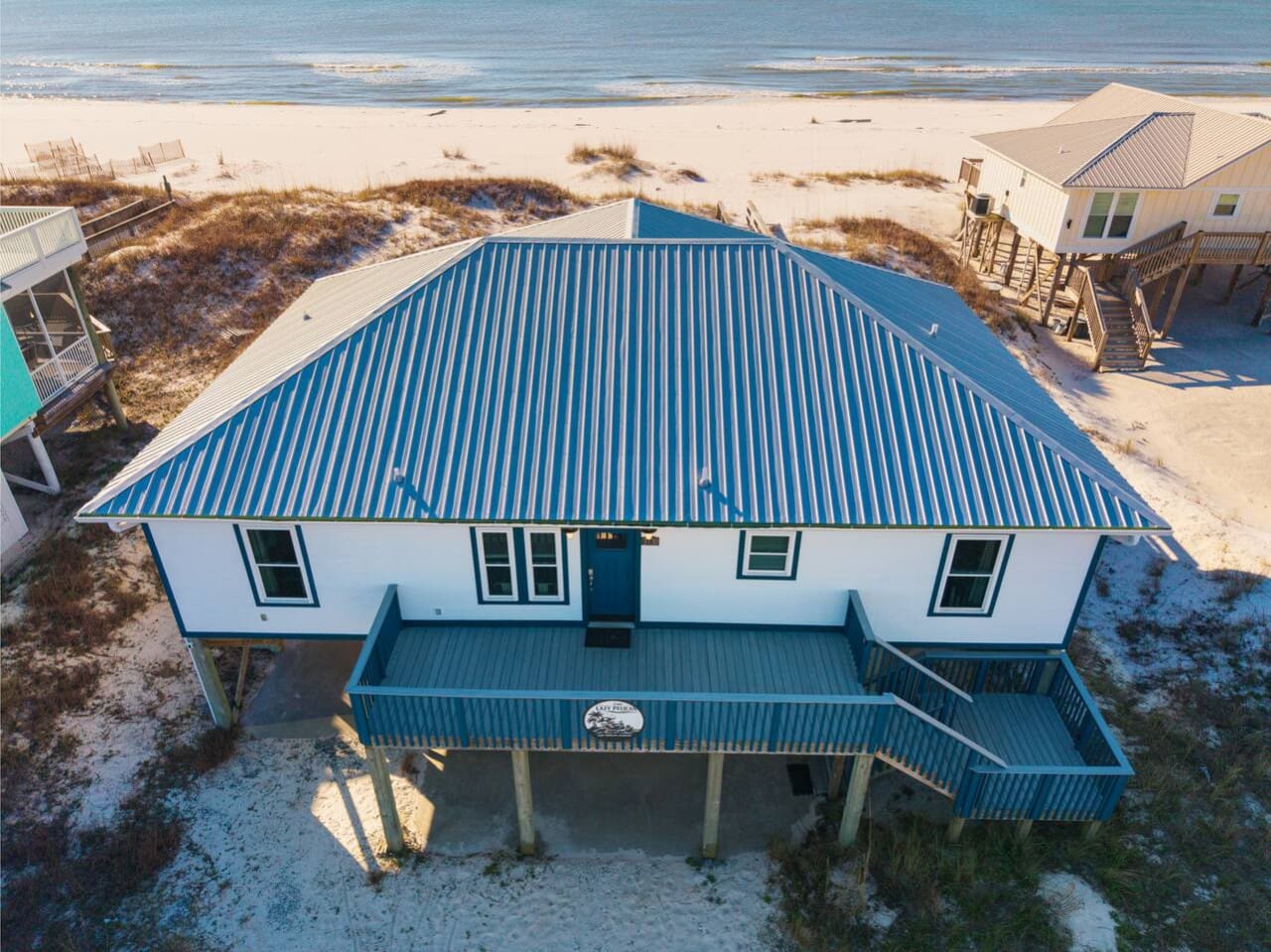 This stunning beachfront home features a massive blue metal roof and sits right on the sand with direct ocean views.