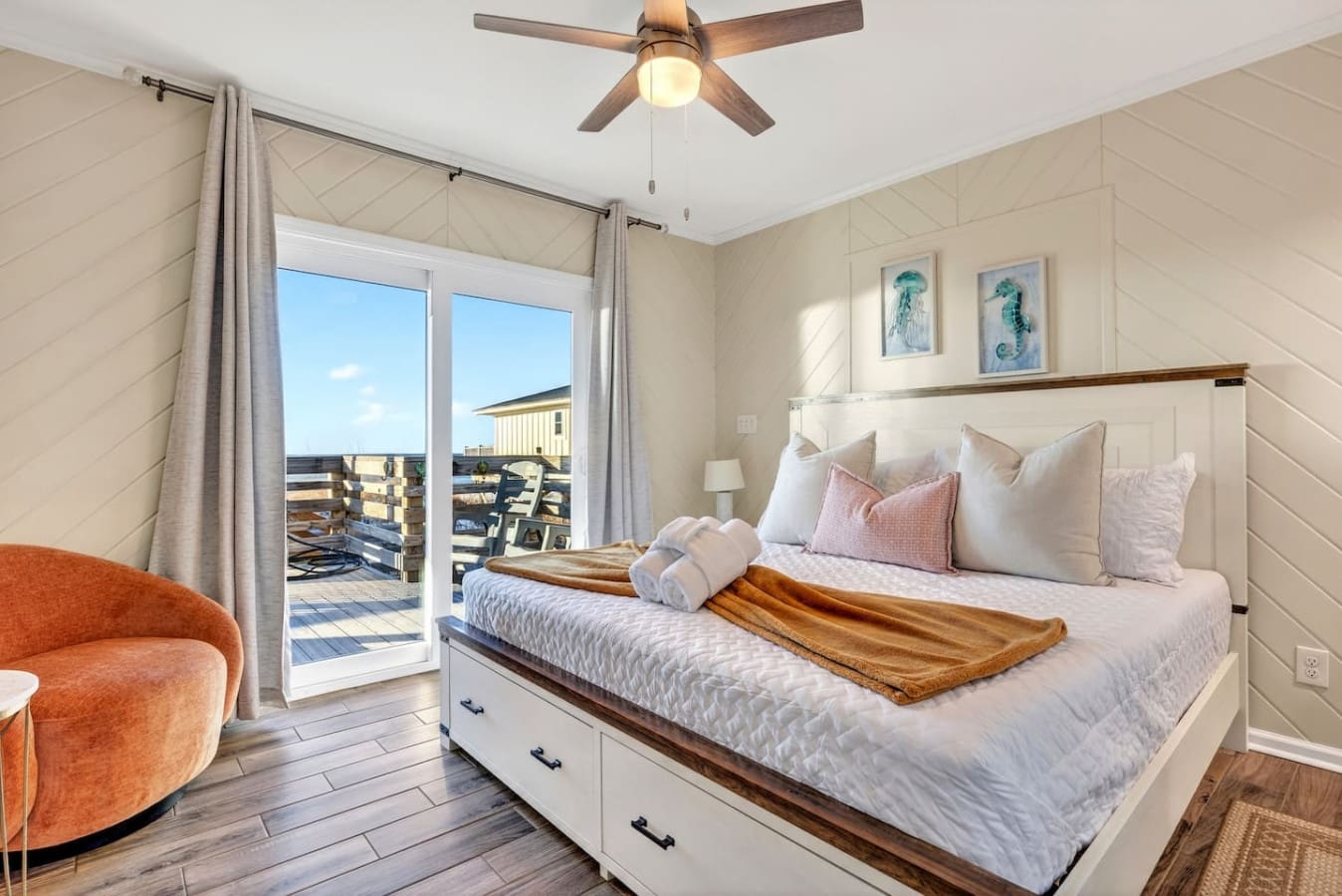Wake up to ocean views from your private deck in this bright, beachy bedroom with shiplap walls and a cozy reading nook.