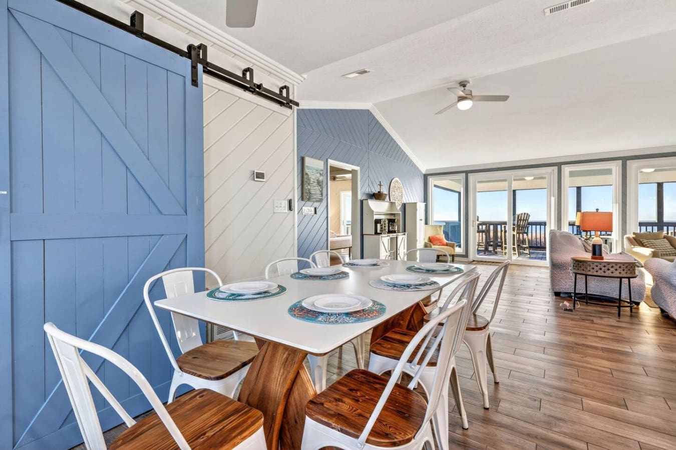 This stunning open-concept dining and living space features soaring ceilings, a sliding barn door, and incredible ocean views from every angle.