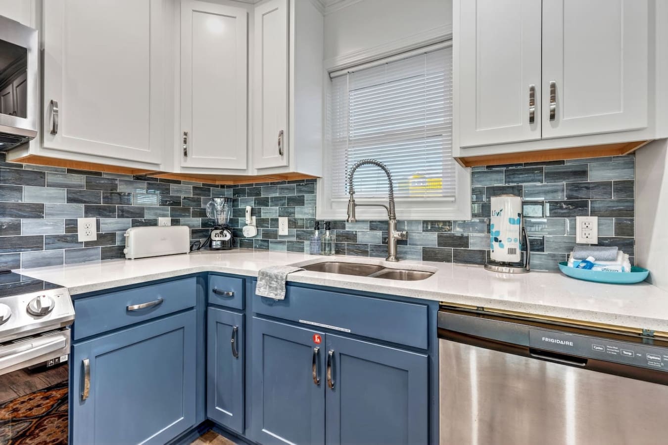 This stunning kitchen features a two-tone cabinetry design with white uppers, blue lowers, and sleek stainless steel appliances.