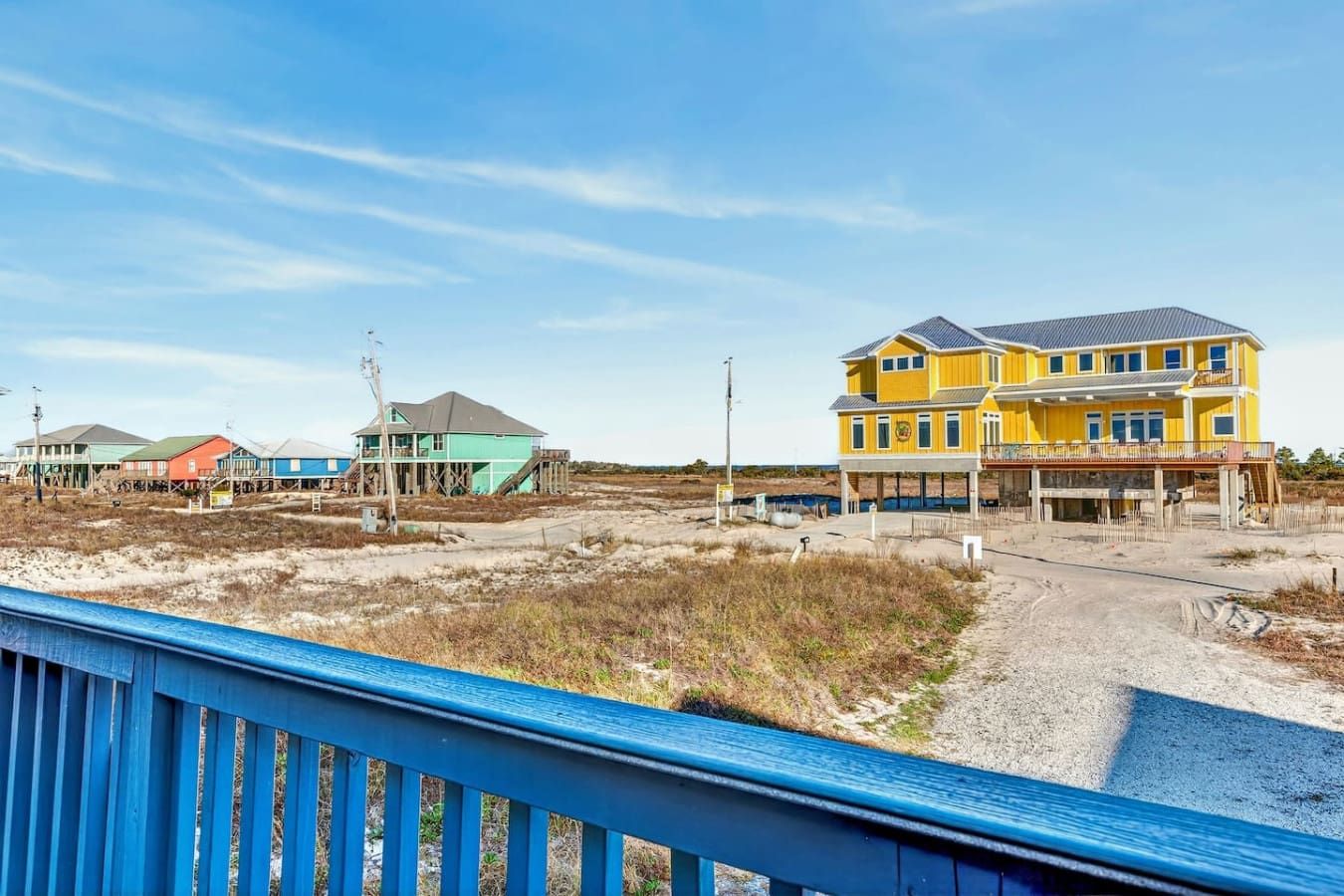Colorful beachfront homes on stilts with wide-open ocean views and pristine sandy shores.