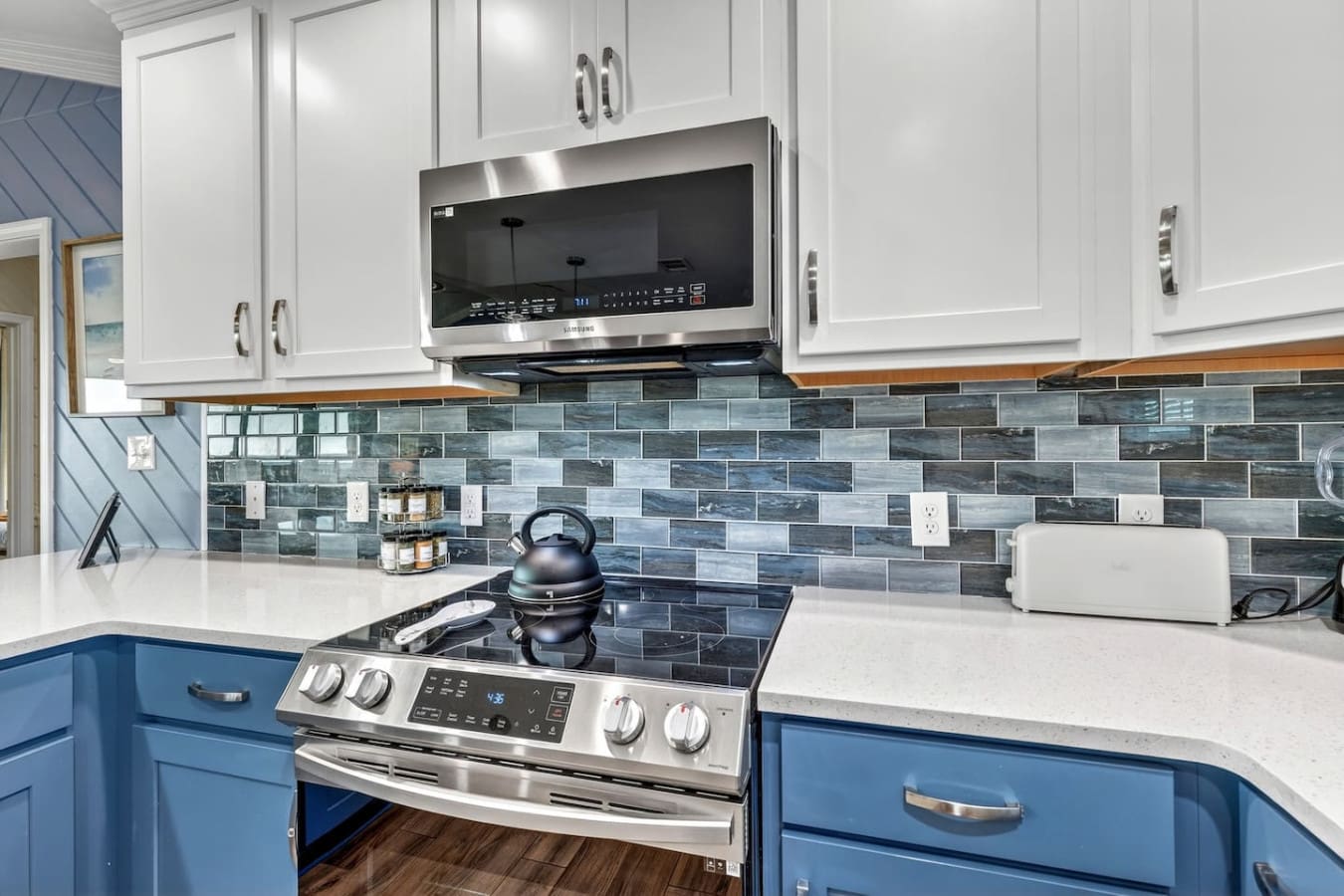 This modern kitchen features sleek stainless steel appliances, crisp white cabinetry, and a gorgeous blue-gray tile backsplash.