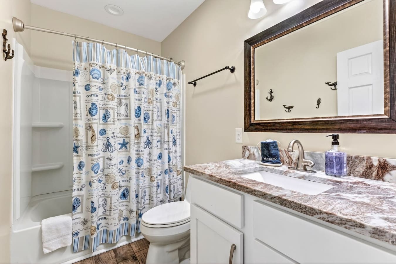 This fresh, nautical-themed bathroom features dual vanity, granite countertops, and a spacious walk-in shower.